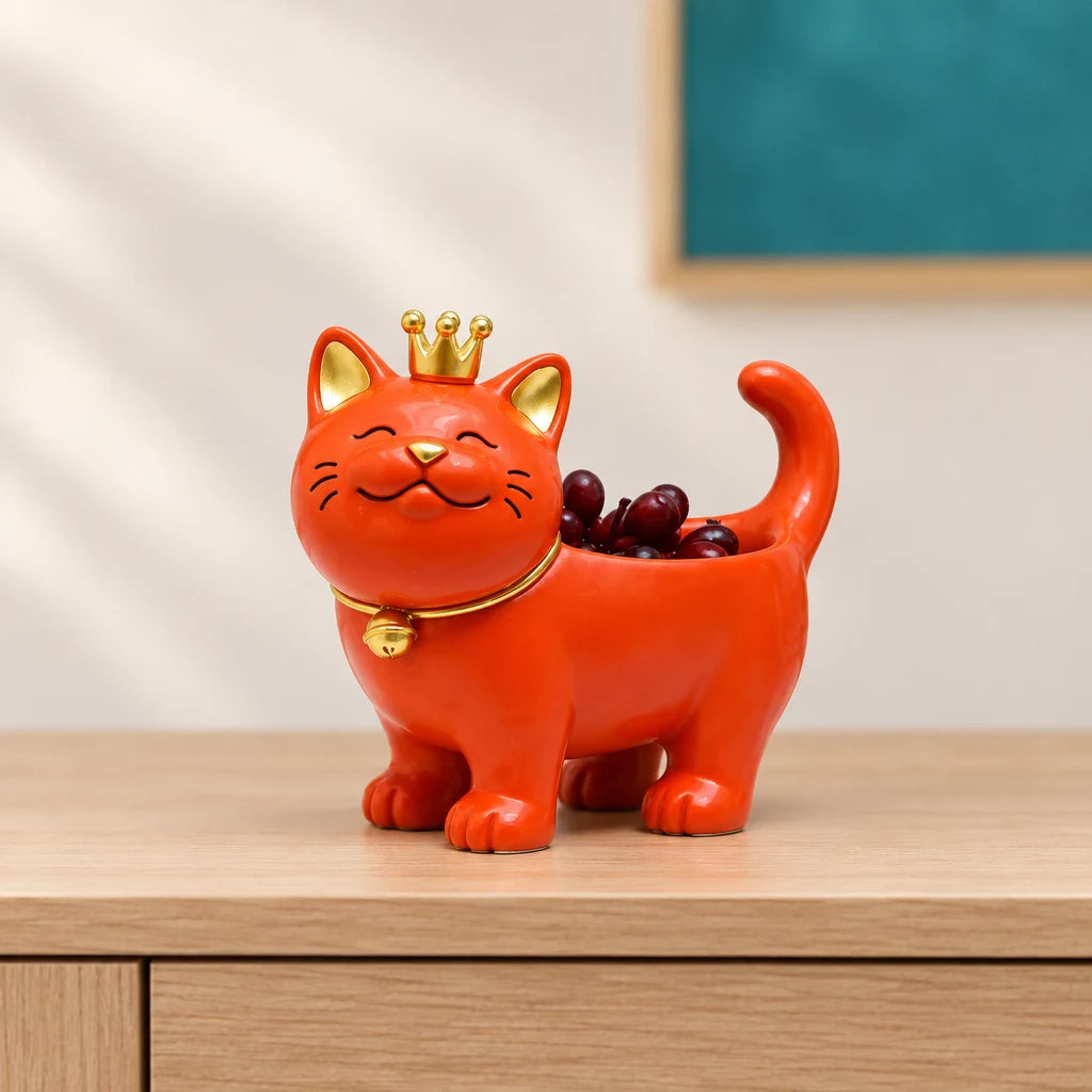 Orange lucky cat decor figurine with gold crown on wooden table beside blue wall art