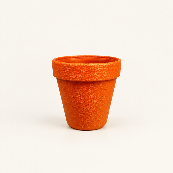 Extra large orange plant pot with textured surface on plain cream background