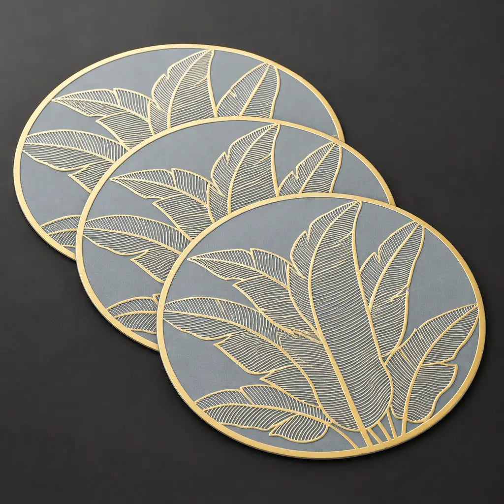 Three round grey and gold leaf pattern table mats on dark surface