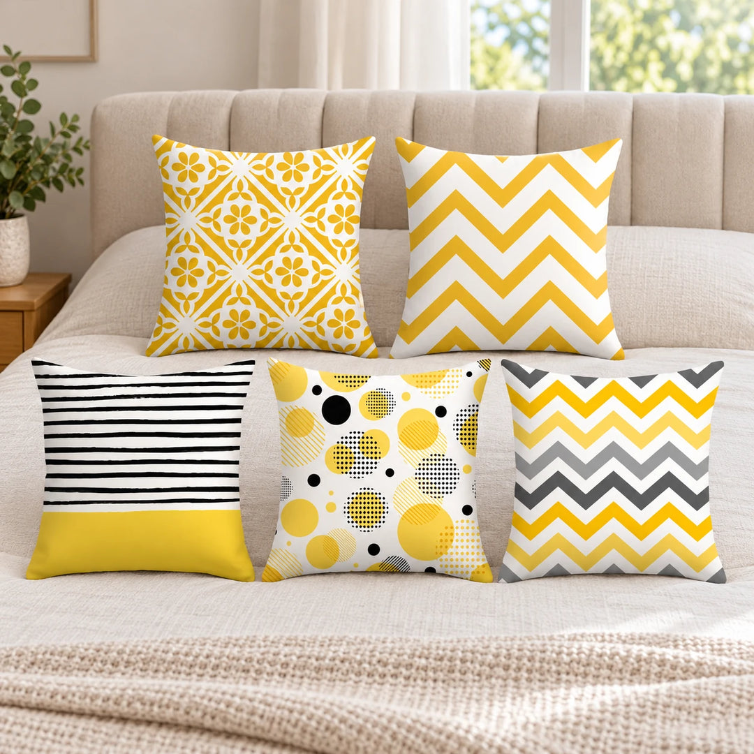 Five yellow, grey and black Prairie cushion covers styled on a bed