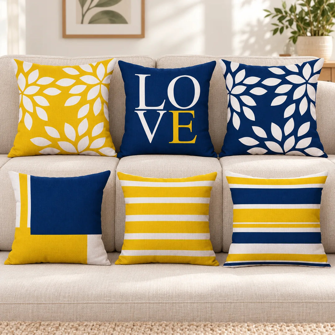 Six Quiet Nest cushion covers with their original navy, mustard and white leaf, stripe, block and LOVE prints on a sofa