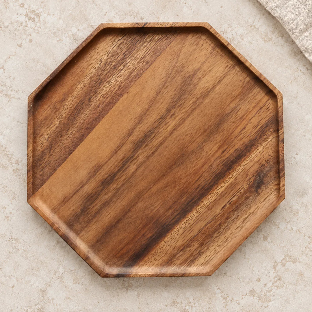 Single octagon wooden serving tray with diagonal natural wood grain on a light stone tabletop