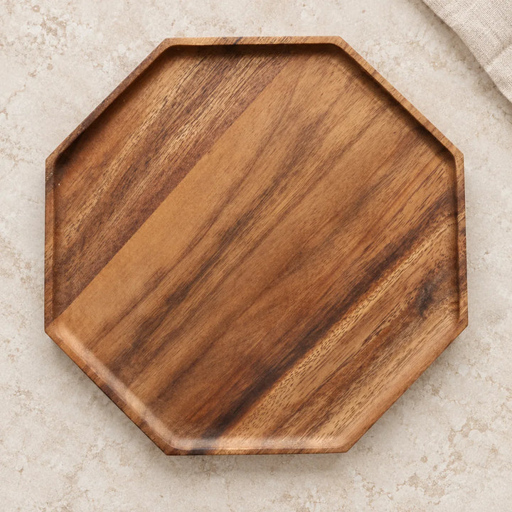Single octagon wooden serving tray with diagonal natural wood grain on a light stone tabletop