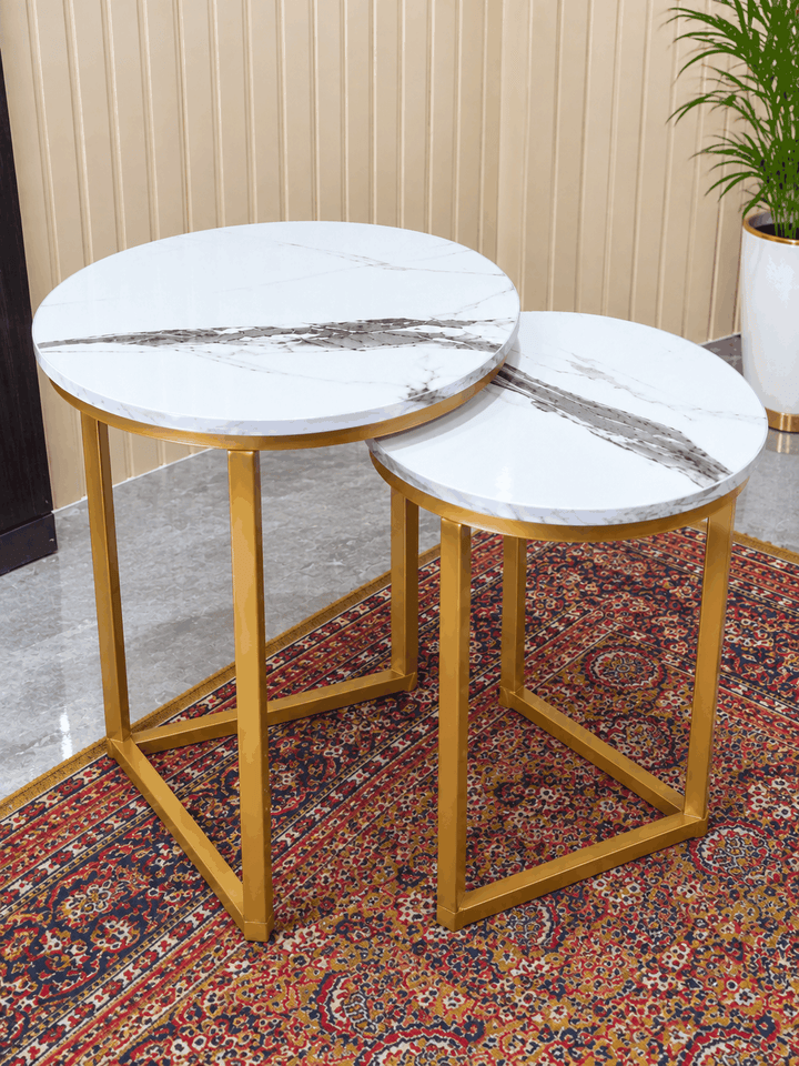 Round white marble nesting side tables overlapping on traditional rug near plant