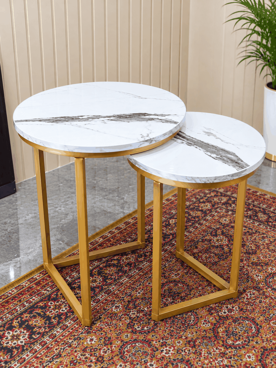 Close view of white marble nesting tables with gold frames on patterned carpet