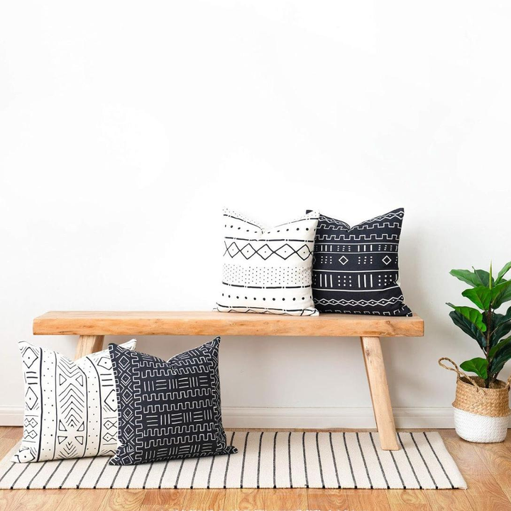 Black and white tribal print cushion covers on wooden bench in bright room