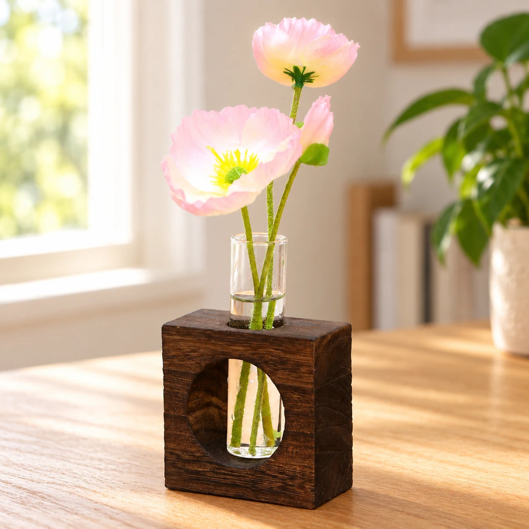 Dark wooden block and glass test-tube vase with pink flowers in natural window light