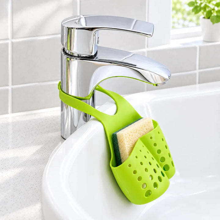 Green silicone sink organizer holding a sponge, hanging from a kitchen tap