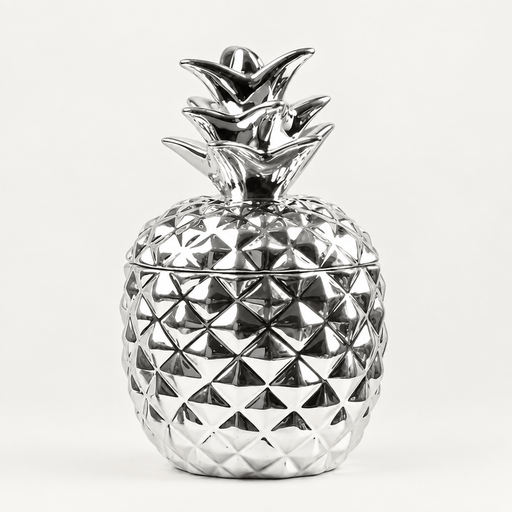 Shiny silver ceramic pineapple jar with leaf lid on white background
