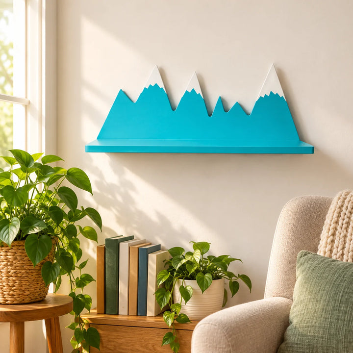 Sky blue mountain-shaped floating shelf with white peaks in a styled kids room with a natural plant