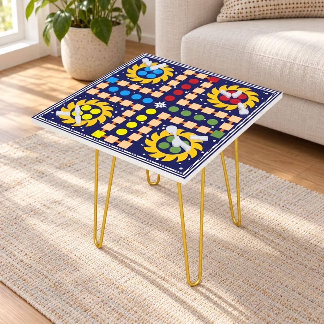Square Ludo game table with printed navy board and gold hairpin legs in a daylight room