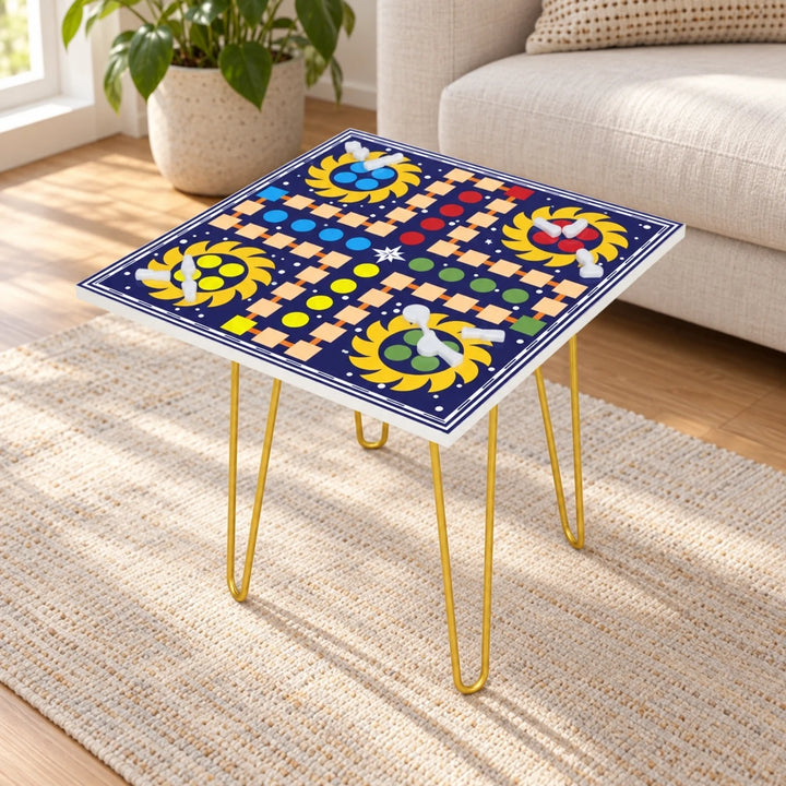 Square Ludo game table with printed navy board and gold hairpin legs in a daylight room