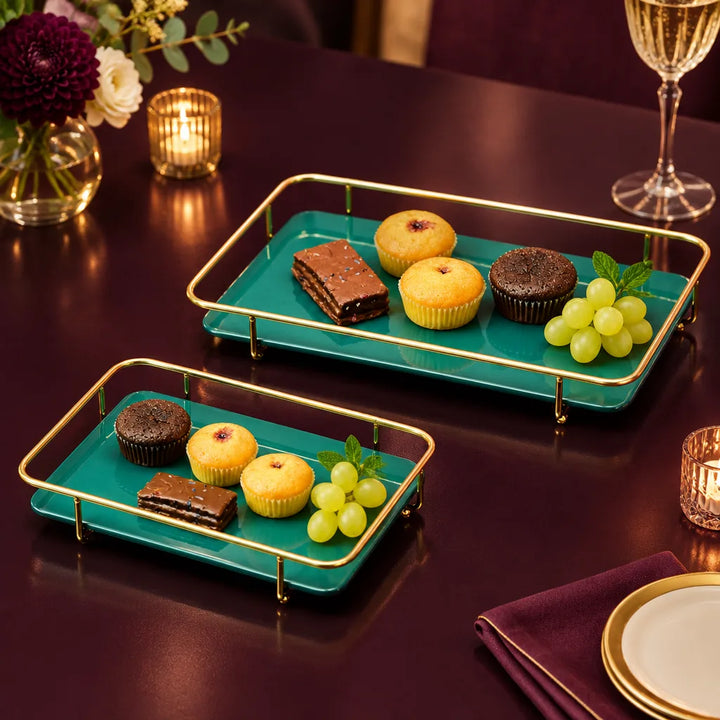 Two teal rectangular serving trays with gold rails holding desserts