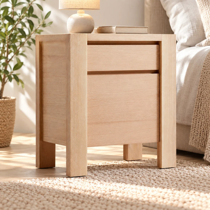 Teetta pale wood bedside table styled with a lamp and book beside a bed