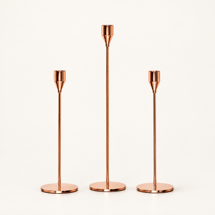 Three rose gold stick candle holders in different heights on white background