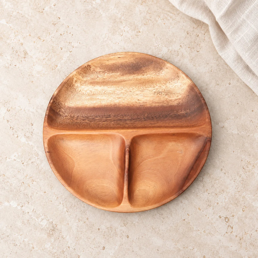 Empty round wooden serving platter with three compartments on a light stone tabletop