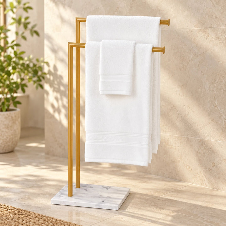 Two-bar towel rack with Akil Gold powder-coated poles and white marble-effect base in a sunlit bathroom