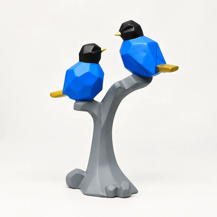 Blue geometric bird decor sculpture pair perched on grey tree branch, white background