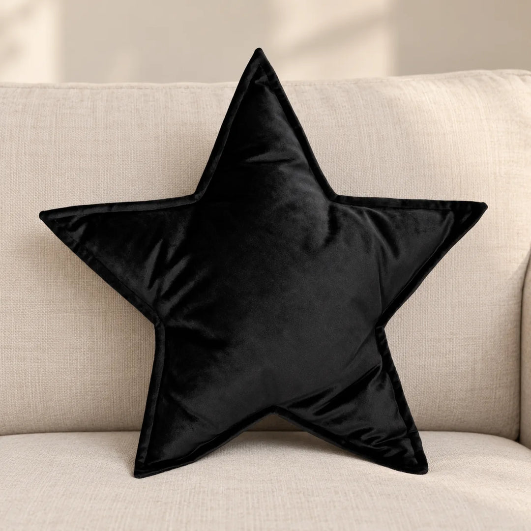 One black Virellea velvet star-shaped filled cushion on a neutral sofa