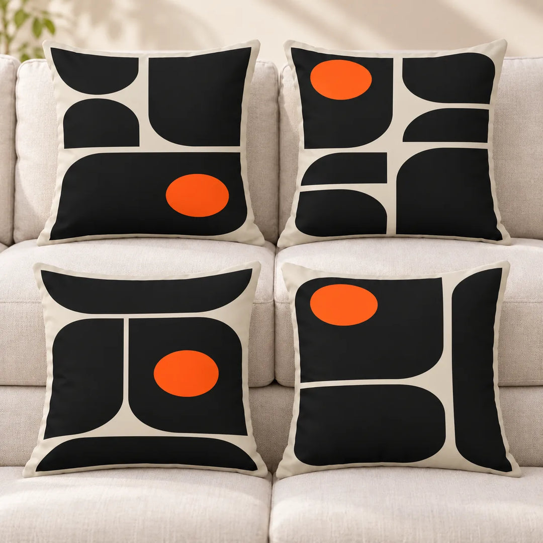 Four Viresta cushion covers with distinct black and ivory curved geometric prints and orange discs on a neutral sofa