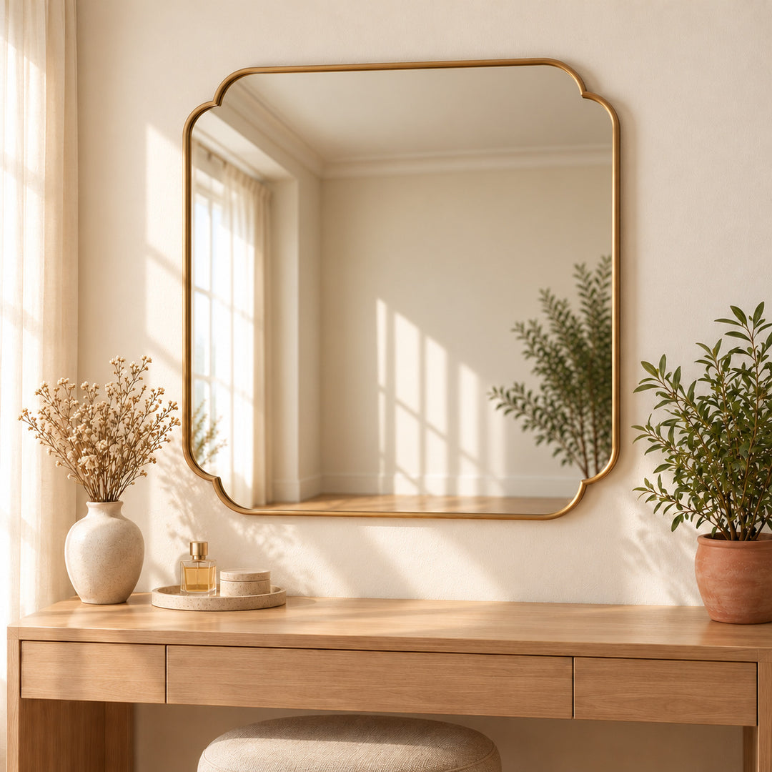 Scalloped corner wall mirror above a dressing table with perfume tray and greenery. Digitally styled visualization.