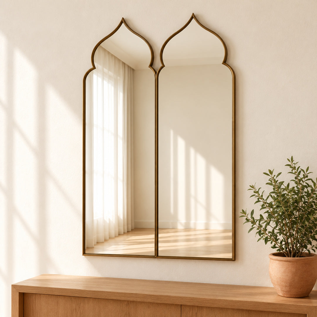 Moorish double arch mirror with brass tone frame and potted green plant.
