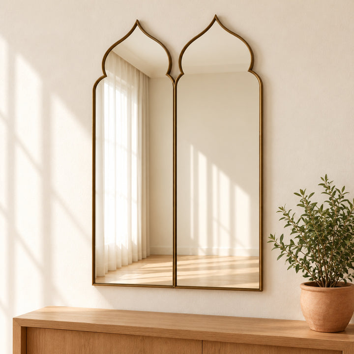 Moorish double arch mirror with brass tone frame and potted green plant.