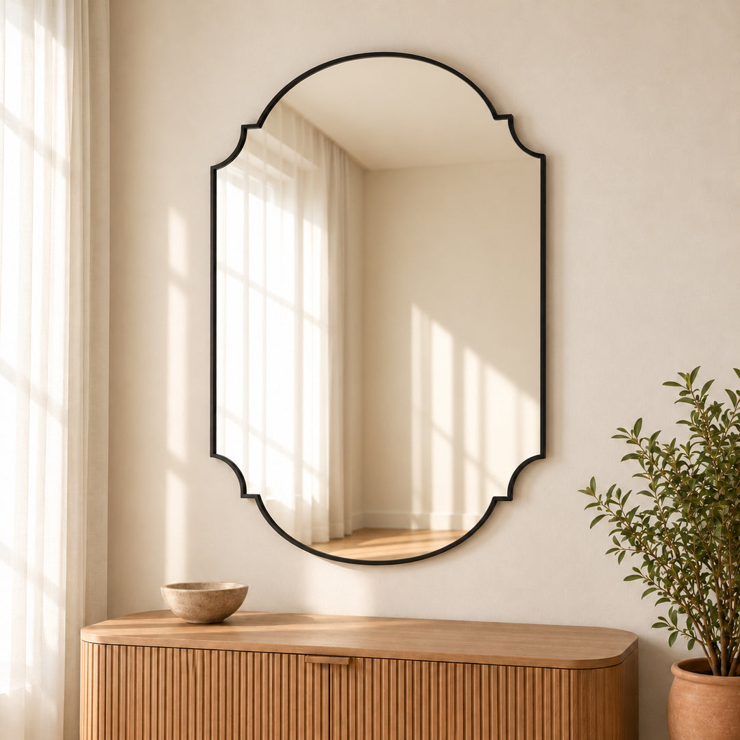 Black shield arch wall mirror in a digitally styled room with a leafy plant.