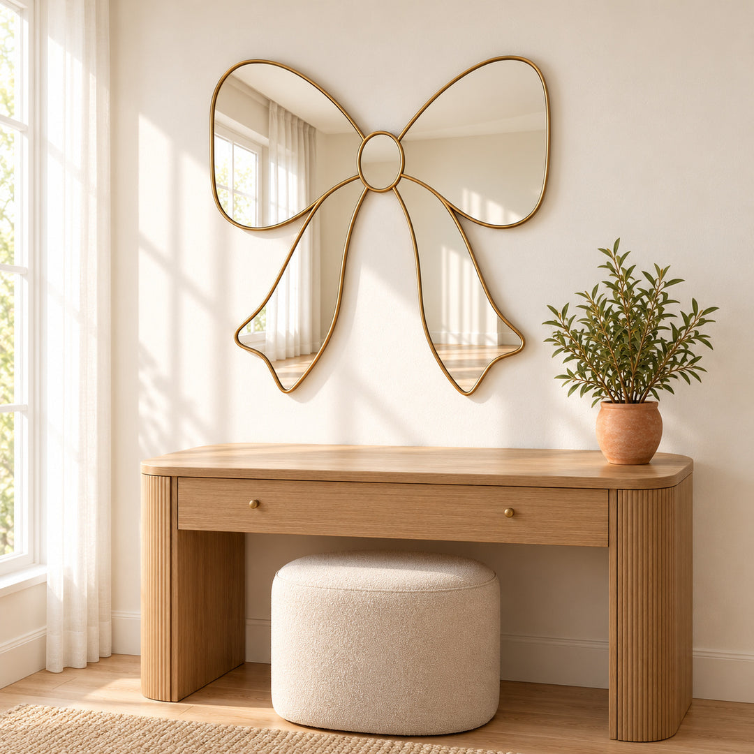 Bow ribbon wall mirror above a wooden dressing table with stool and greenery. Digitally styled visualization.