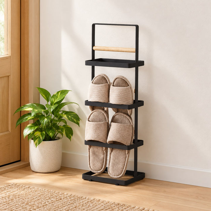 Black Iru vertical shoe stand with natural wood bars and beige slippers against an entryway wall