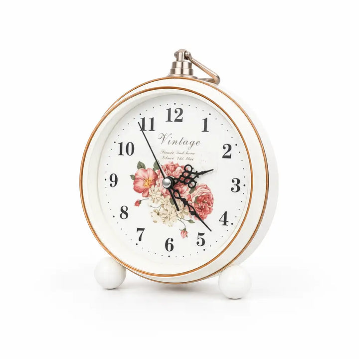 Round white alarm clock with rose gold rim and floral face, front view on white background