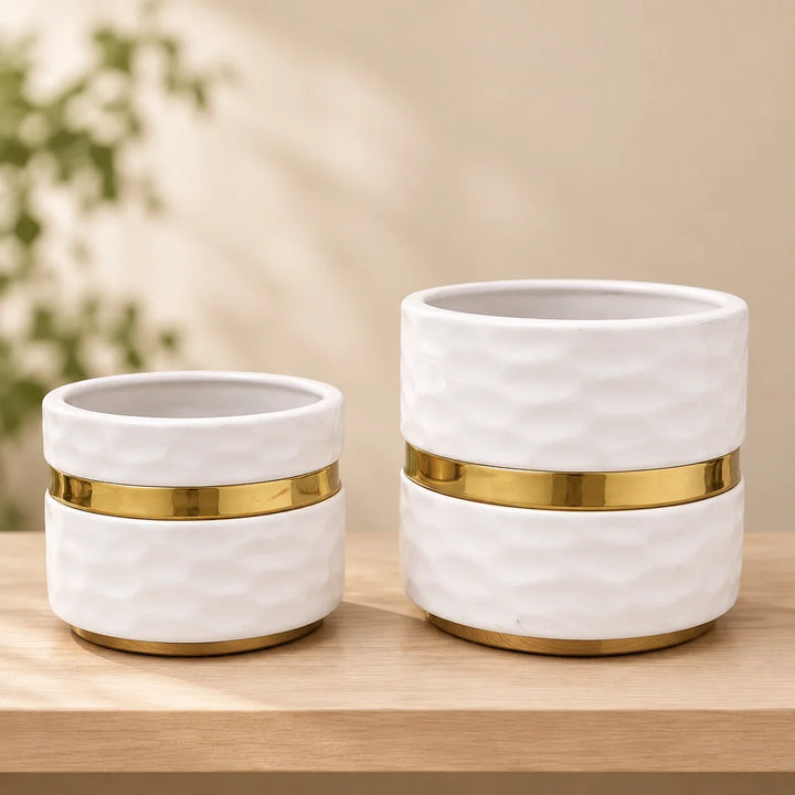Pair of white textured ceramic vases with gold band on wooden shelf