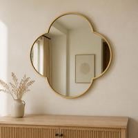 Large quatrefoil four lobed wall mirror with a slim gold frame above a fluted sideboard