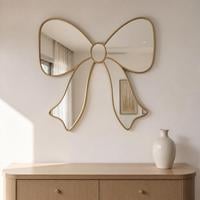 Bow shaped wall mirror with gold framed loops and tails hung above a wooden sideboard