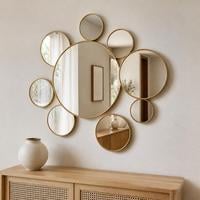 Cluster of overlapping round wall mirrors in mixed sizes with gold frames above a sideboard