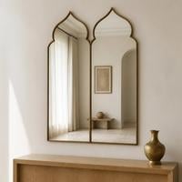 Double pointed arch wall mirror with a slim brass frame above a wooden console table