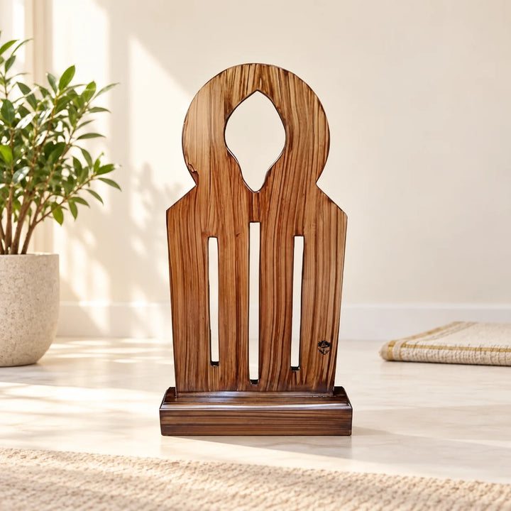 Wooden arched prayer sutrah with three vertical slots in a natural-light prayer corner beside a plant