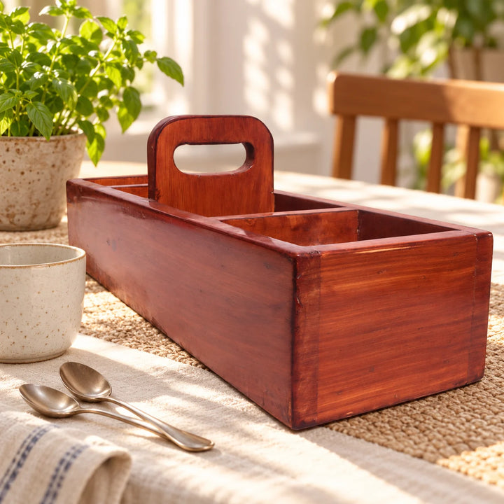 Brown wooden divided serving tray with carrying handle on a dining table beside a cup and natural plant