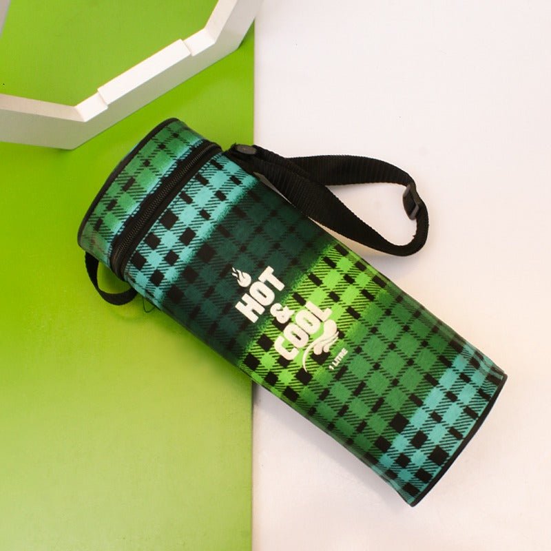 Green checked thermos storage bag lying tilted with black strap on green surface